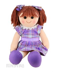 Penny is an adorable doll with a soft cloth body and brown hair tied in pigtails with purple plaid bows and wears a matching purple tartan dress with a purple ribbon around her waist.